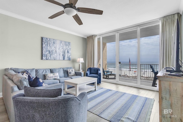 living room with expansive windows, crown molding, a water view, and wood finished floors