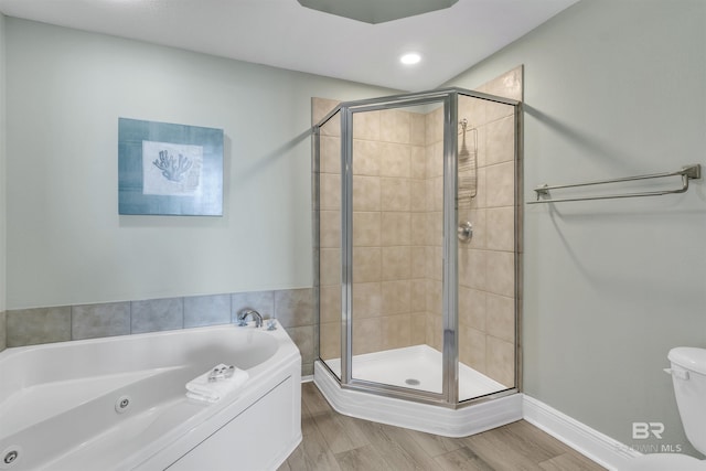 bathroom with baseboards, wood finished floors, a jetted tub, and a stall shower