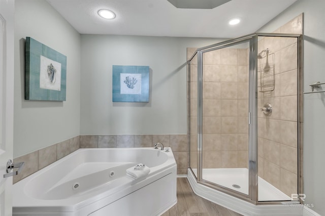 bathroom with a jetted tub, wood finished floors, and a stall shower