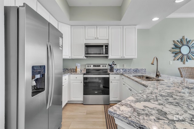 kitchen featuring a sink, stainless steel appliances, light stone counters, and light wood finished floors