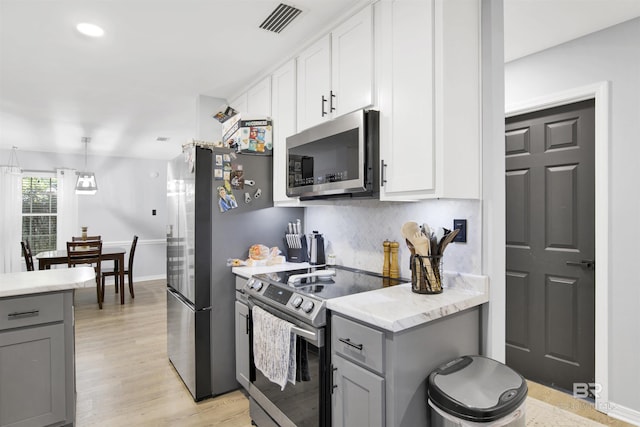 kitchen featuring appliances with stainless steel finishes, gray cabinetry, backsplash, and light wood-style flooring