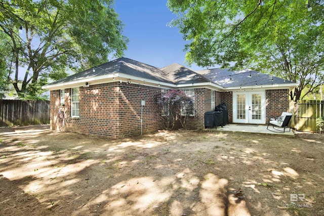 rear view of property with french doors, fence, brick siding, and a patio