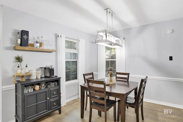 dining room featuring light wood finished floors, baseboards, and a dry bar