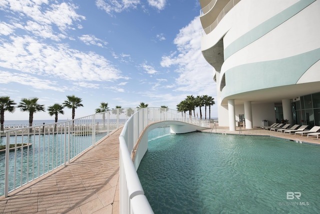 pool featuring a patio and a water view