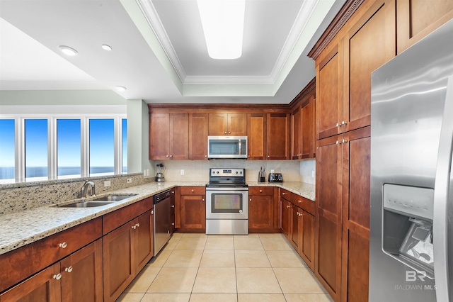 kitchen featuring a sink, ornamental molding, stainless steel appliances, a raised ceiling, and backsplash