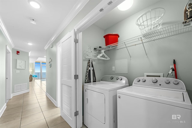 laundry room featuring visible vents, crown molding, washer and clothes dryer, laundry area, and light tile patterned flooring