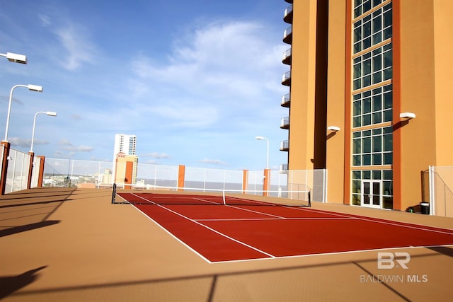 view of tennis court featuring a city view, community basketball court, and fence