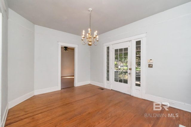 empty room featuring ceiling fan with notable chandelier and hardwood / wood-style floors