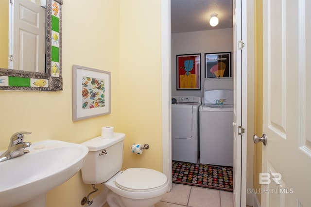 bathroom with tile patterned flooring, sink, washer and clothes dryer, and toilet