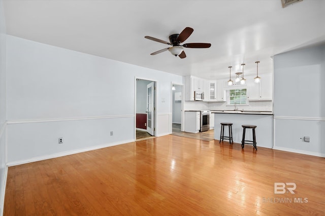 5175 W Somerset Dr, Mobile, AL 36619 - unfurnished living room with a ceiling fan, a sink, light wood finished floors, and baseboards