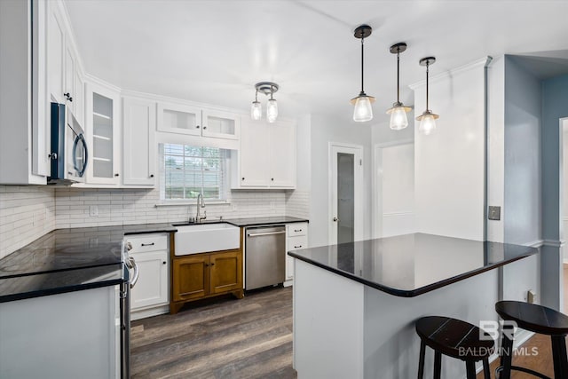 5175 W Somerset Dr, Mobile, AL 36619 - kitchen with appliances with stainless steel finishes, a sink, dark countertops, dark wood-style flooring, and backsplash