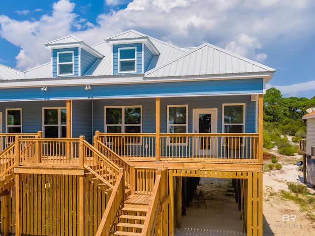 back of property with metal roof, a porch, stairway, and an attached garage