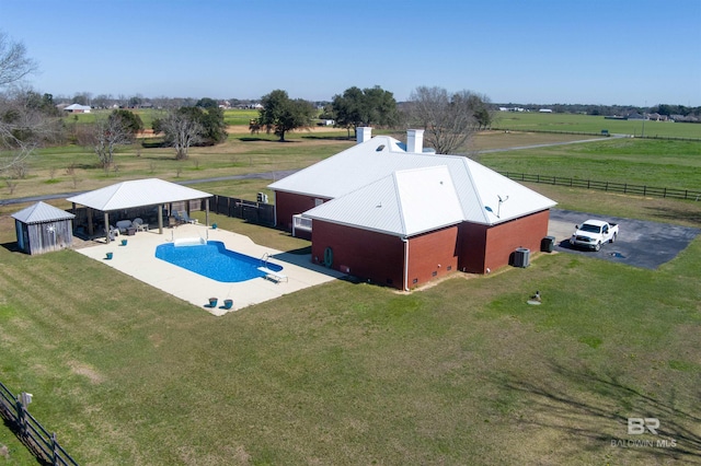 view of pool featuring an outbuilding, a rural view, fence, and a lawn