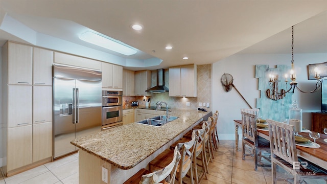 28105 Perdido Beach Blvd Unit C211, Orange Beach, AL 36561 - kitchen featuring wall chimney exhaust hood, appliances with stainless steel finishes, a peninsula, a kitchen bar, and backsplash