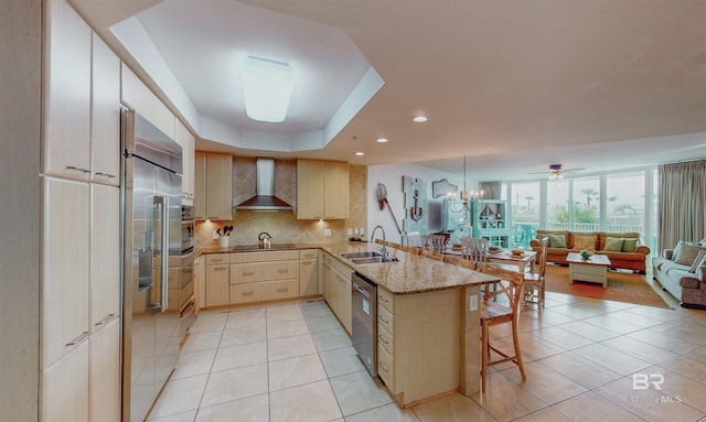 28105 Perdido Beach Blvd Unit C211, Orange Beach, AL 36561 - kitchen featuring wall chimney range hood, open floor plan, a peninsula, decorative backsplash, and stainless steel appliances