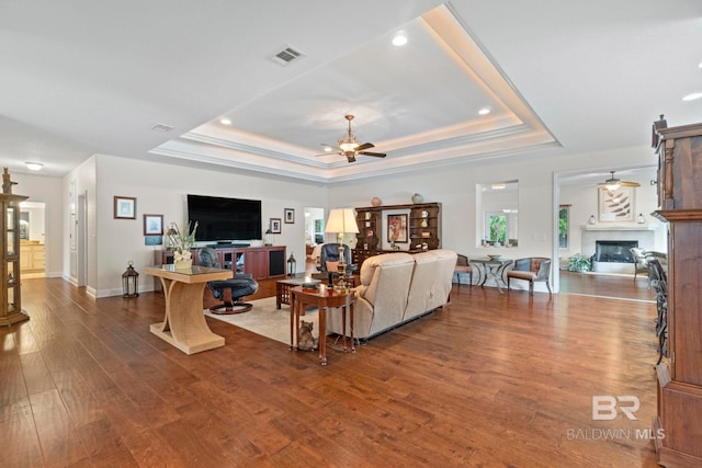 8664 Foxtail Loop, Pensacola, FL 32526 - living room featuring ceiling fan, a tray ceiling, wood finished floors, a glass covered fireplace, and recessed lighting