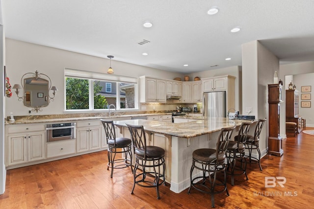 8664 Foxtail Loop, Pensacola, FL 32526 - kitchen with appliances with stainless steel finishes, light wood finished floors, a breakfast bar area, light stone countertops, and recessed lighting
