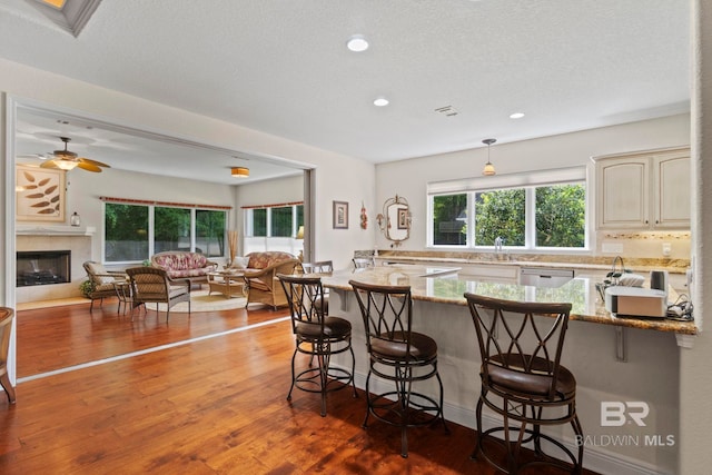 8664 Foxtail Loop, Pensacola, FL 32526 - kitchen with a breakfast bar area, cream cabinets, open floor plan, wood-type flooring, and recessed lighting
