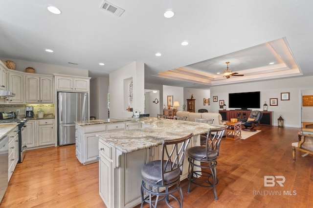 8664 Foxtail Loop, Pensacola, FL 32526 - kitchen featuring stainless steel appliances, a kitchen bar, open floor plan, light stone counters, and light wood-style flooring