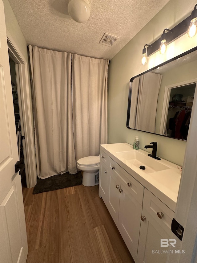1010 E Hamilton Bridges Dr, Mobile, AL 36695 - bathroom with wood finished floors, a textured ceiling, toilet, vanity, and a spacious closet