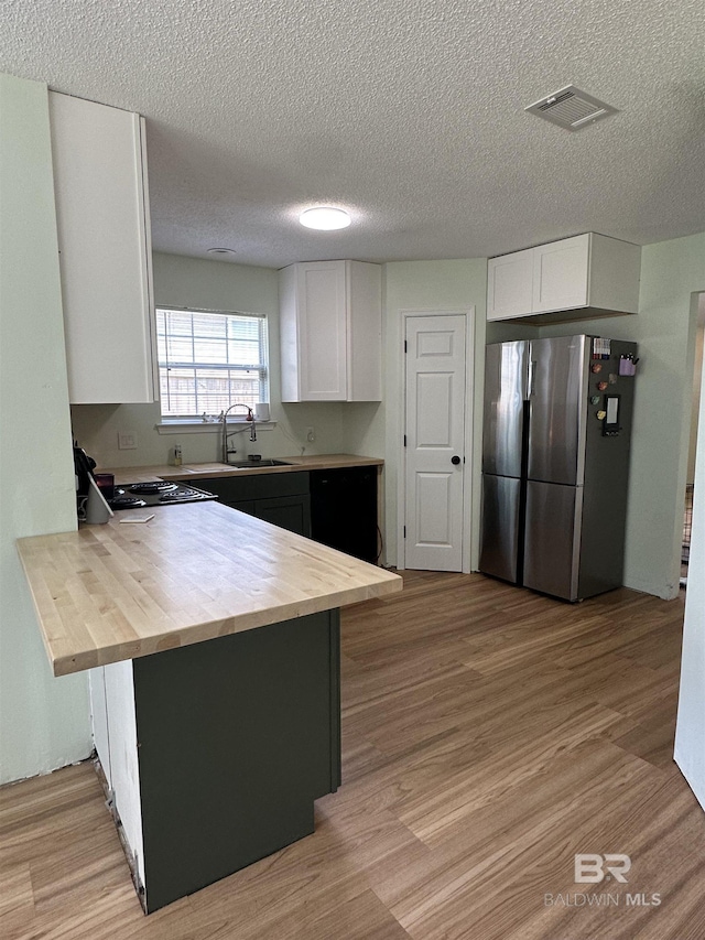 1010 E Hamilton Bridges Dr, Mobile, AL 36695 - kitchen with freestanding refrigerator, a peninsula, wooden counters, a sink, and white cabinetry