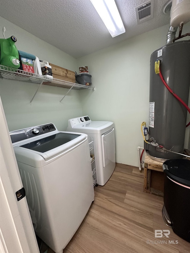 1010 E Hamilton Bridges Dr, Mobile, AL 36695 - laundry area featuring water heater, washer and dryer, light wood-style flooring, and a textured ceiling