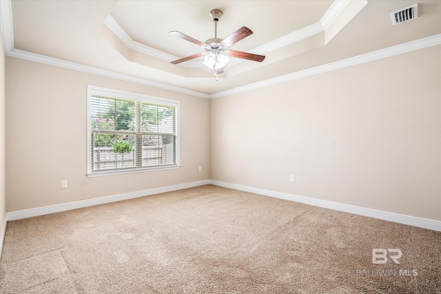 empty room with ornamental molding, a raised ceiling, and carpet floors