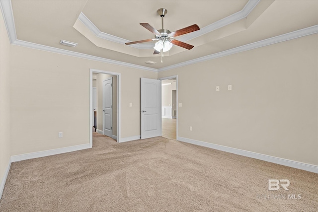 unfurnished bedroom featuring ornamental molding, a walk in closet, light colored carpet, ceiling fan, and a tray ceiling