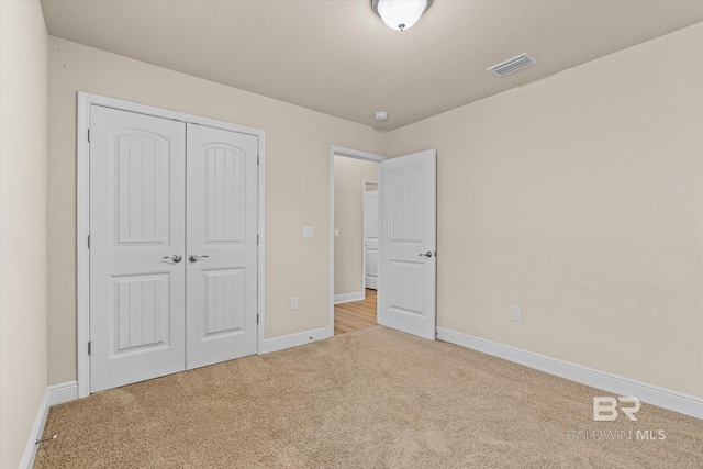 unfurnished bedroom with light carpet and a closet