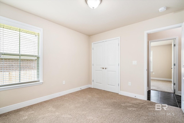 unfurnished bedroom featuring a closet and dark colored carpet