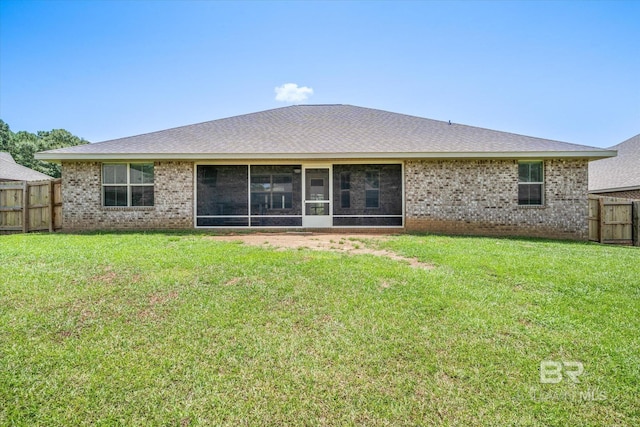 rear view of house with a sunroom and a lawn