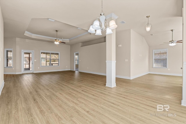 unfurnished living room featuring a tray ceiling, ornamental molding, light hardwood / wood-style floors, ceiling fan with notable chandelier, and ornate columns