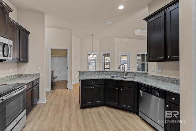 kitchen featuring light stone counters, stainless steel appliances, sink, and light wood-type flooring