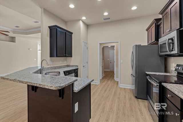 kitchen with light stone counters, a kitchen bar, light hardwood / wood-style flooring, and appliances with stainless steel finishes