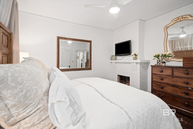 bedroom with ceiling fan and a brick fireplace