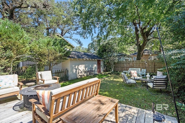 wooden terrace featuring a lawn and an outdoor living space with a fire pit