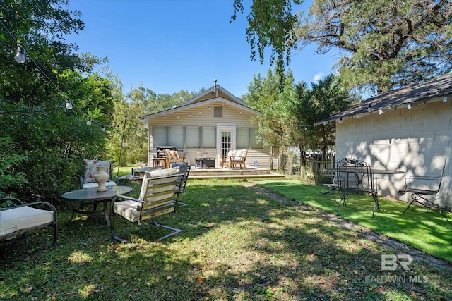 rear view of property featuring a wooden deck and a lawn