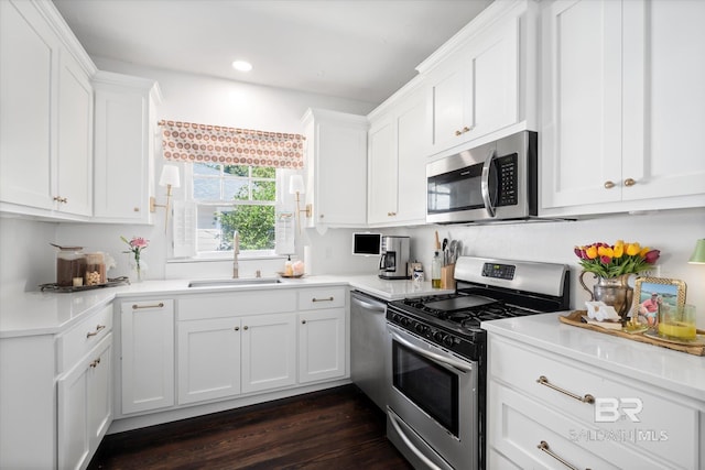 kitchen with appliances with stainless steel finishes, white cabinetry, sink, and dark wood-type flooring