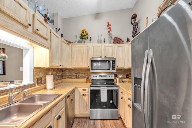 2200 W 2nd St Unit 301-C, Gulf Shores, AL 36542 - kitchen featuring stainless steel appliances, decorative backsplash, a textured ceiling, light wood-type flooring, and light countertops