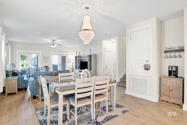 dining space featuring ceiling fan with notable chandelier and light hardwood / wood-style floors