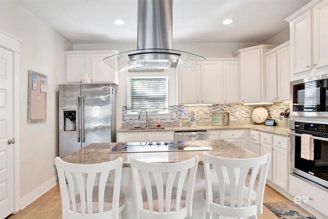 kitchen with white cabinets, appliances with stainless steel finishes, a kitchen island, and sink