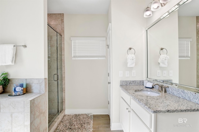 bathroom with hardwood / wood-style floors, vanity, and an enclosed shower