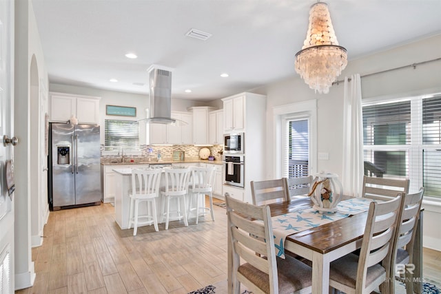 dining room featuring a chandelier, sink, and light hardwood / wood-style floors