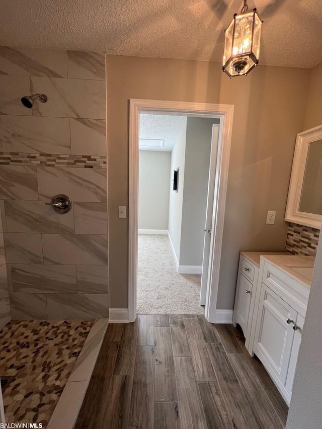 15082 County Road 93, Lillian, AL 36549 - bathroom with vanity, hardwood / wood-style floors, a textured ceiling, and tiled shower