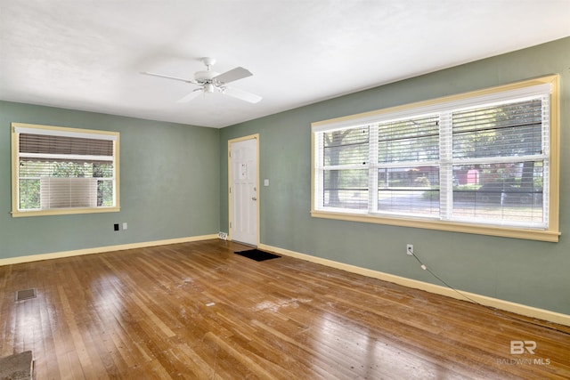 unfurnished room featuring baseboards, ceiling fan, visible vents, and wood-type flooring