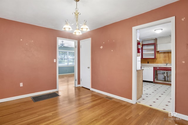 unfurnished dining area with baseboards, light wood-style flooring, visible vents, and a sink