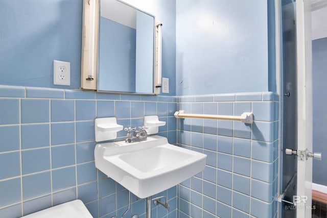 half bathroom featuring a sink and tile walls