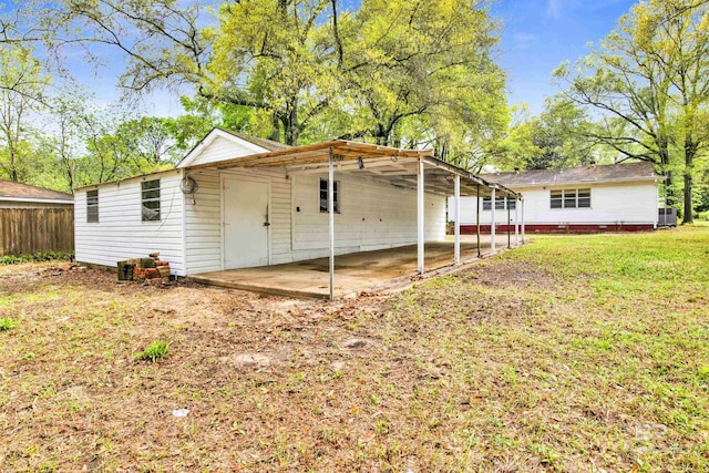 back of property featuring a lawn and a carport