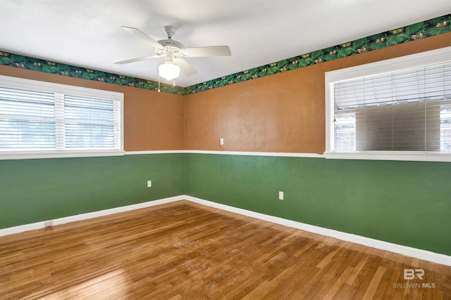unfurnished room with baseboards, wood finished floors, and ceiling fan