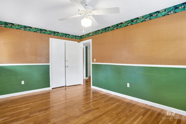 unfurnished room featuring a ceiling fan, baseboards, and wood finished floors